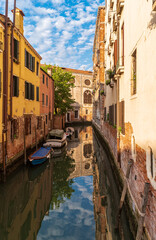 Fototapeta na wymiar View of quiet street and narrow canal with boats along brink. The residential area of Venice, Italy.