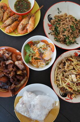 Thai dishes include grilled shrimp, papaya salad, stir-fried moo roasted basil and egg salad, Jae Son mineral water, Lampang, Thailand.