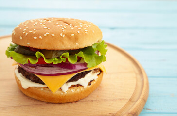Fresh homemade burger on cutting board on blue wooden table.