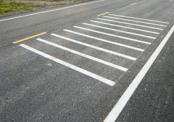 White transverse rumble strips on the asphalt road.