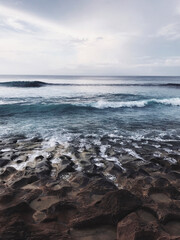 Beautiful balinese landscape. Ocean black sandy coast. White sea foam and dark huge rocks. Bali Island, Indonesia.	