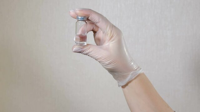 Medical worker holding ampule with Coronavirus, flu or other infection vaccine in hand. glass bottle with transparent vaccine liquid. Health care and medical concepts. 4 k video