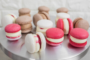 Colorful macaroons on metal stand. Sweet white, red and chocolate macarons in the kitchen