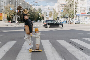 14.09.2020 Vinnitsa, Ukraine: mother brings a child riding a scooter on the crosswalk