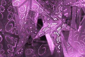 Colorful pink xmas lantern stars at christmas market season. Beautiful shiny star mood lamp in merry advent decoration. Traditional symbol of the best miracle time of the year. Part of series