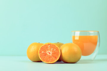 Fresh tangerine orange fruit and juice in glass on color background