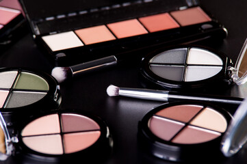 Cosmetic palette and face shadow with brushes lies on a black background