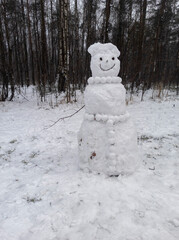 photo of a snowman on a winter day. winter forest. landscape with snow. snowman on the background of the forest in the snow.