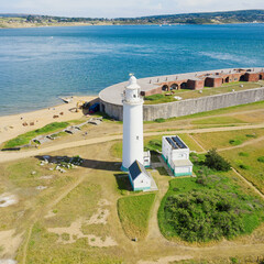 Square - aerial view of Hurst point, in the United Kingdom. Lighthouse by the sea with the castle in the background by the sea. - 414689289