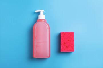 Red dishwashing soap and sponge on blue background. Top view.