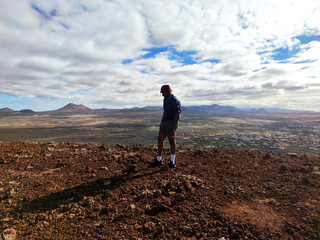 Fototapeta premium Black man with a red hat on top of volcano in Fuerteventura