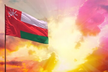 Fluttering Oman flag in top left corner mockup with the space for your text on beautiful colorful sunset or sunrise background.