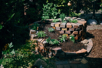herb spiral in garden made of bricks with herbs