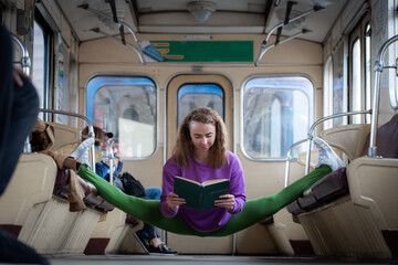 Flexible woman sitting on the split in the subway car and reading book. Concept of individuality and creativity.