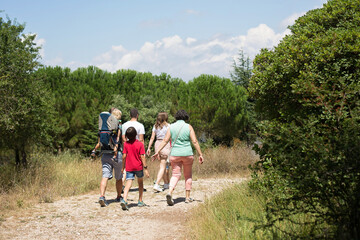 Obraz premium Big family with toddler in a backpack carrier and friends, hiking in the mountains