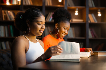 two young african women reading books in the library 
