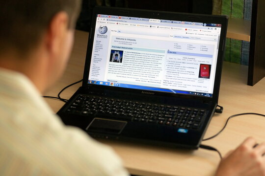 Russia Samara July 2020: A young man during the coronavirus epidemic watches wikipedia on a laptop at night.