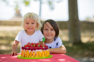 Sweet little blond toddler boy, celebrating his third birthday in a park with siblings and friends