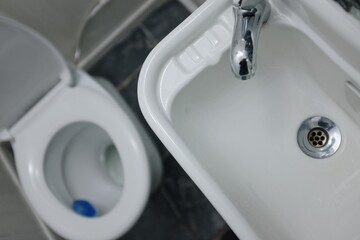 white restroom, toilet, toilet paper and sink composition
