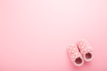 Beautiful soft warm baby girl slippers on light pink table background. Pastel color. Closeup. Comfortable home shoes. Empty place for text. Top down view.