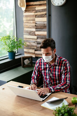Young businessman with a mask working in his office on laptop. COVID - 19 virus protection. Healthy lifestyle..