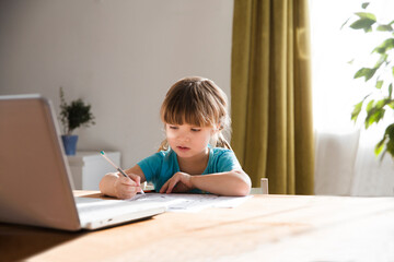 child girl is using a laptop and study online with video call teacher at home. homeschooling, distant learning