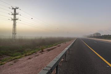 Fototapeta premium Heavy fog over an agricultural field and intercity expressway on an early winter morning in northern Israel