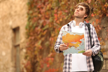 Traveler with world map near building outdoors