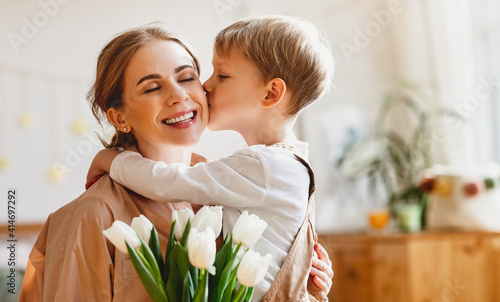 tender son kisses the happy mother and gives her a bouquet of tulips, congratulating her on mother's day