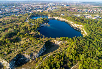 Fototapeta na wymiar Krakow, Poland. Zakrzowek lake with steep cliffs in place of former flooded limestone quarry in Twardowski Rocks. Popular recreational place. Aerial view at sunrise