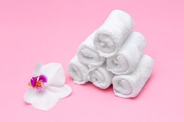 Fototapeta na wymiar white cotton towels on a pink background with a flower