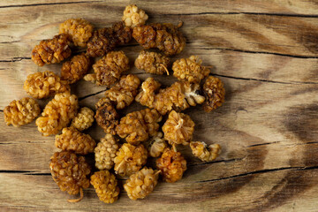Dried mulberry fruit on a wooden chopping board. Artificial, soft light from two flash units