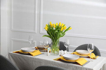 Beautiful Easter table setting with yellow tulips indoors
