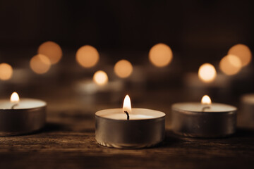 Fototapeta na wymiar Close-up image of many burning candles in the dark. Bokeh effect background.