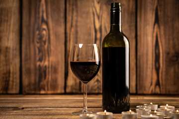 Red wine glass and bottle red wine on old wooden background. 