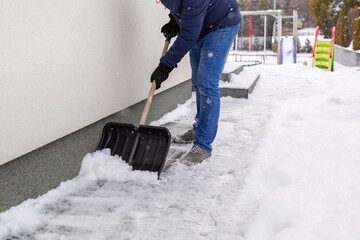 Snow removal of the driveway in front of the house with a shovel