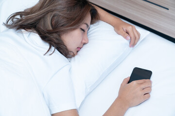 Young asian women lying in bed texting and checking social apps in smartphone on bed before after she sleeping at night. Mobile addict concept.