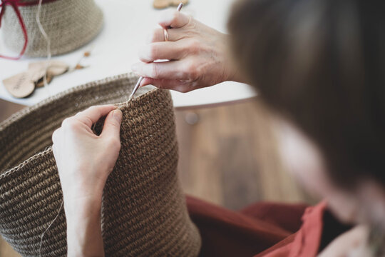 The woman is crocheting from environmentally friendly materials. Jute fiber for home decor. Home hobby of weaving thick-walled rope baskets. Handwork in the interior. Knitted jute and rope baskets.