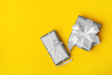 Trendy attractive minimalistic gray gifts on the yellow background. Colors of 2021. Merry Christmas, St. Valentine's Day, Happy Birthday and other holidays concept.