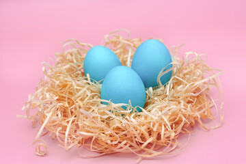 Easter eggs in blue colors in a nest on a pink backgraund. The concept of stylish decoration for Easter