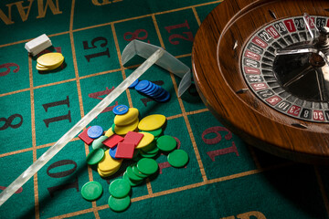 Roulette in legno isolata sopra un tavolo da gioco verde con fiches colorate - obrazy, fototapety, plakaty