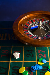 Roulette in legno isolata sopra un tavolo da gioco verde con fiches colorate - obrazy, fototapety, plakaty