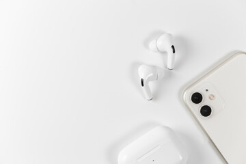 white wireless headphones on a white background. White smartphone