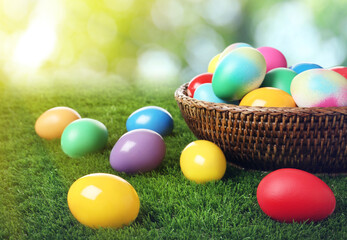 Wicker basket with bright painted Easter eggs on green grass