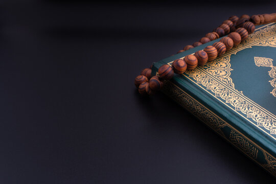Holy Quran with arabic calligraphies translation meaning of Al-Quran and Rosary or Tasbih on black background. Ramadan,Hajj, Islamic and Copy Space concept