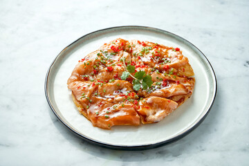 Mexican cuisine dish - tostada with salmon, sweet and sour sauce, onions, cilantro, served in a white plate on a marble background. Close up, selective focus