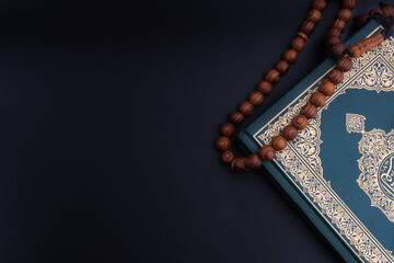 Holy Quran with arabic calligraphies translation meaning of Al-Quran and Rosary or Tasbih on black...