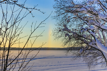 Between the trees, you can see a rainbow streak in the sky on a winter sunny day.February, 16.2021.