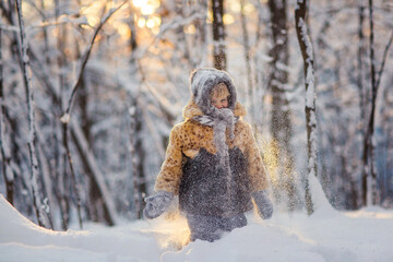 little girl in a fur coat playing with snow