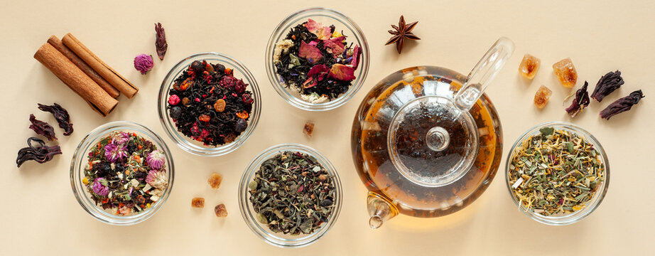 A Set Of Different Types Of Green, Black And Herbal Tea Next To The Kettle Filled With Hot Brewed Tea On A Beige Background. Delicious Organic Drinks. View From Above. Banner